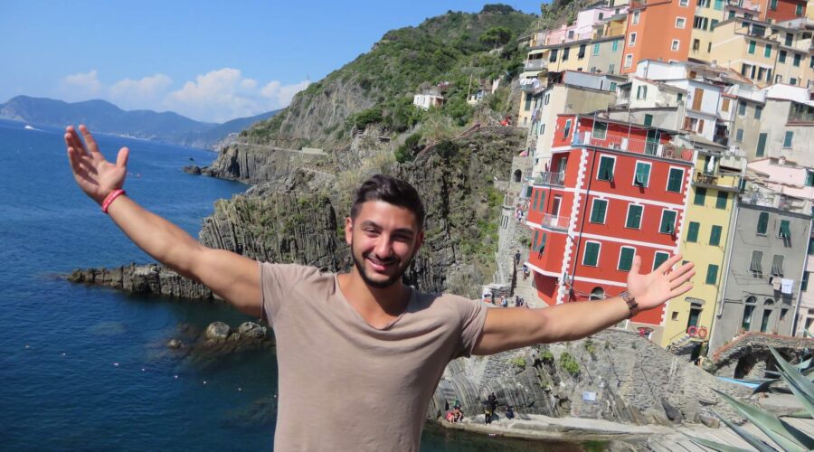 Guy standing in front of Riomaggiore with his arms spread out